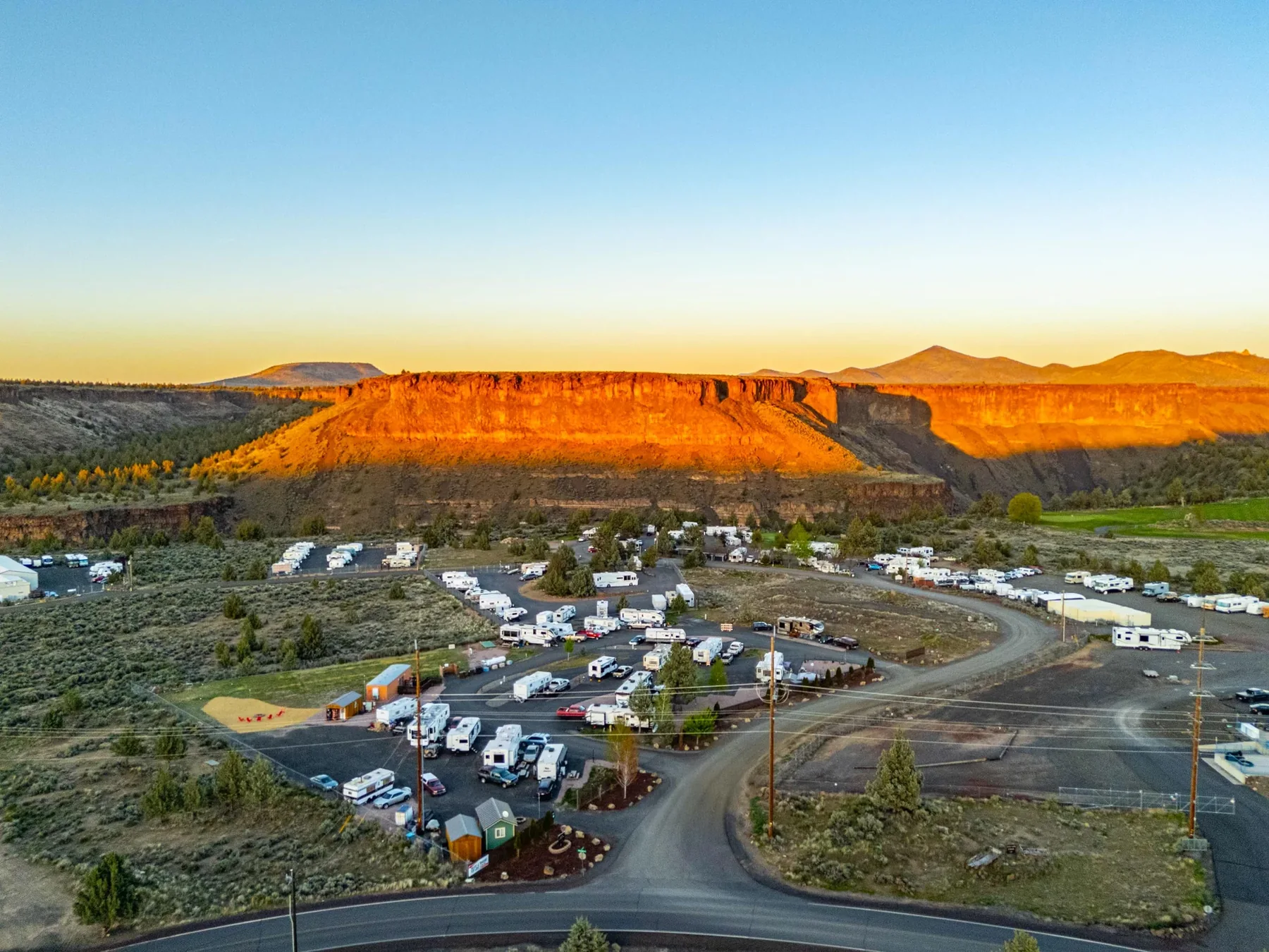 Aerial view of Copper Ridge RV Resort at golden sunset with canyon wall glowing orange